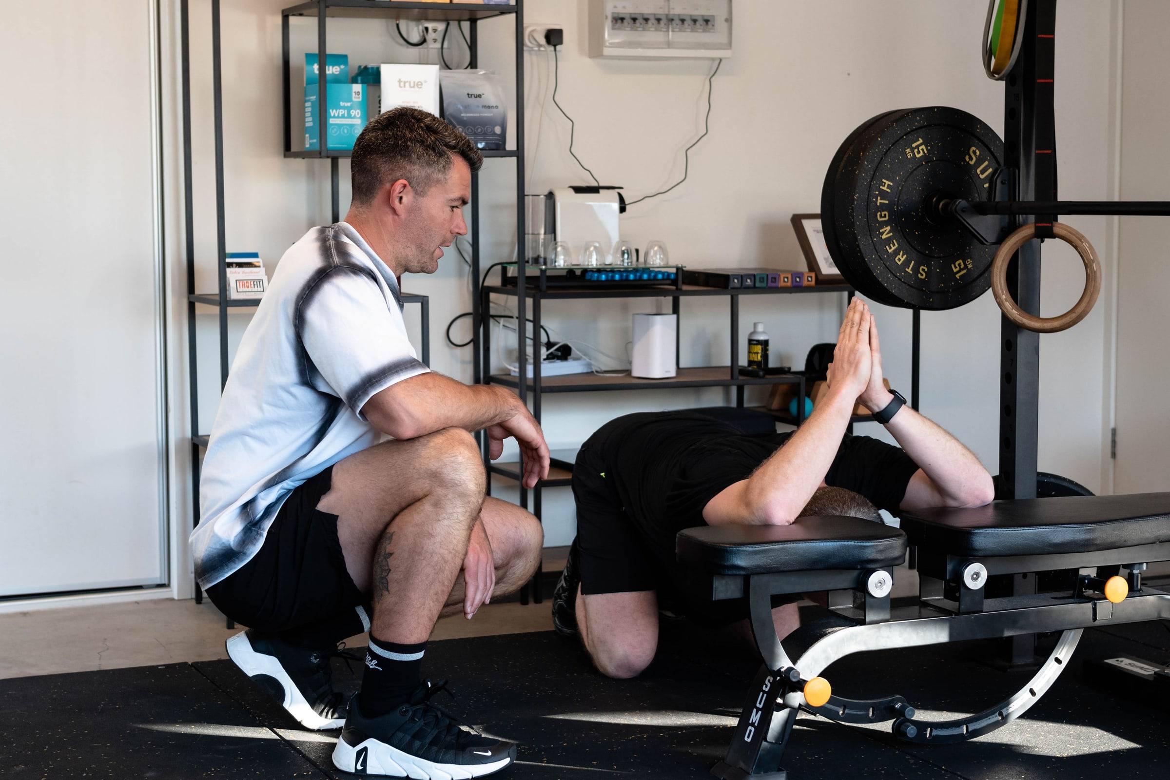 Richy kneeling beside a client to coach a stretch