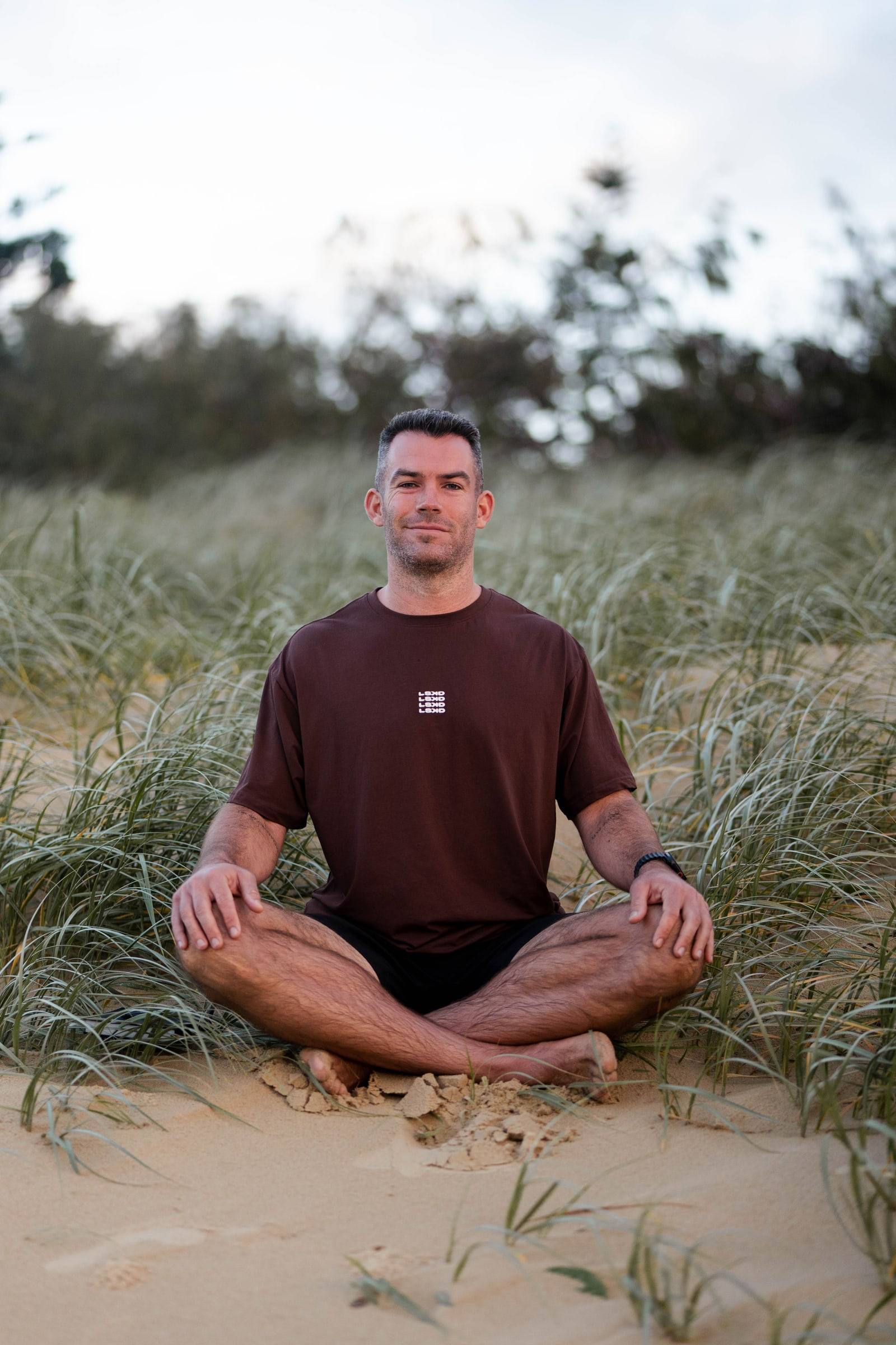 Richy sitting cross-legged in the dunes at dawn