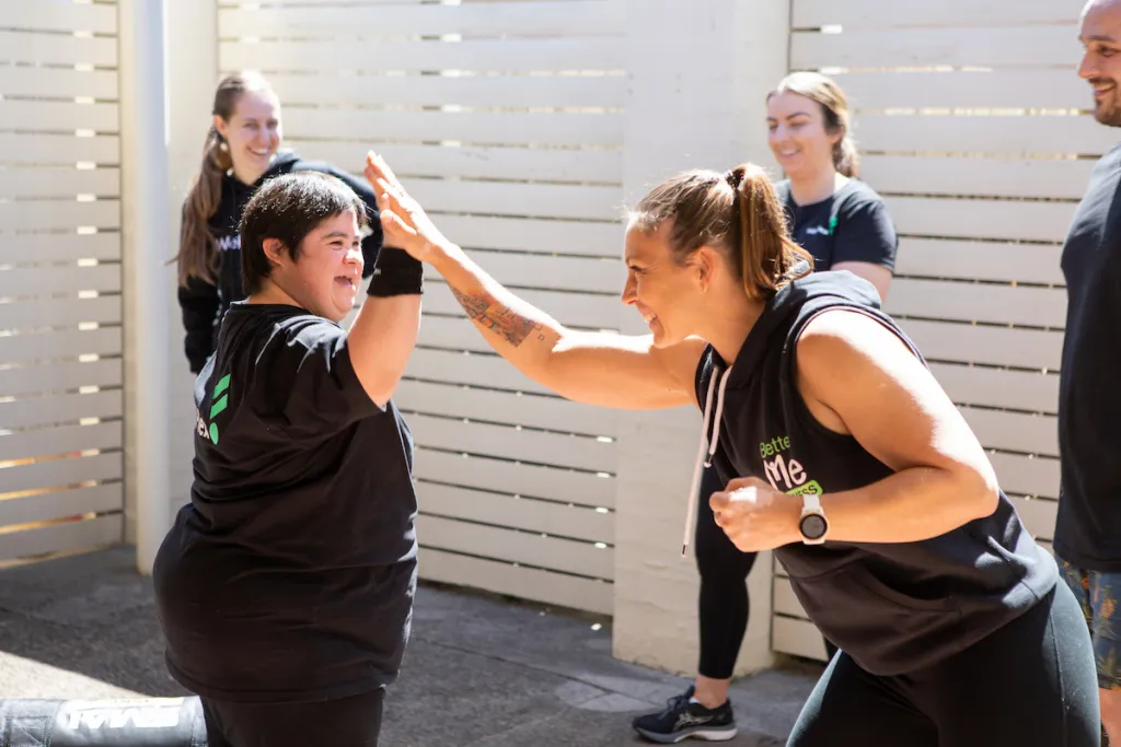 A supportive personal trainer assisting an NDIS participant with strength training, promoting mobility, confidence, and independence.