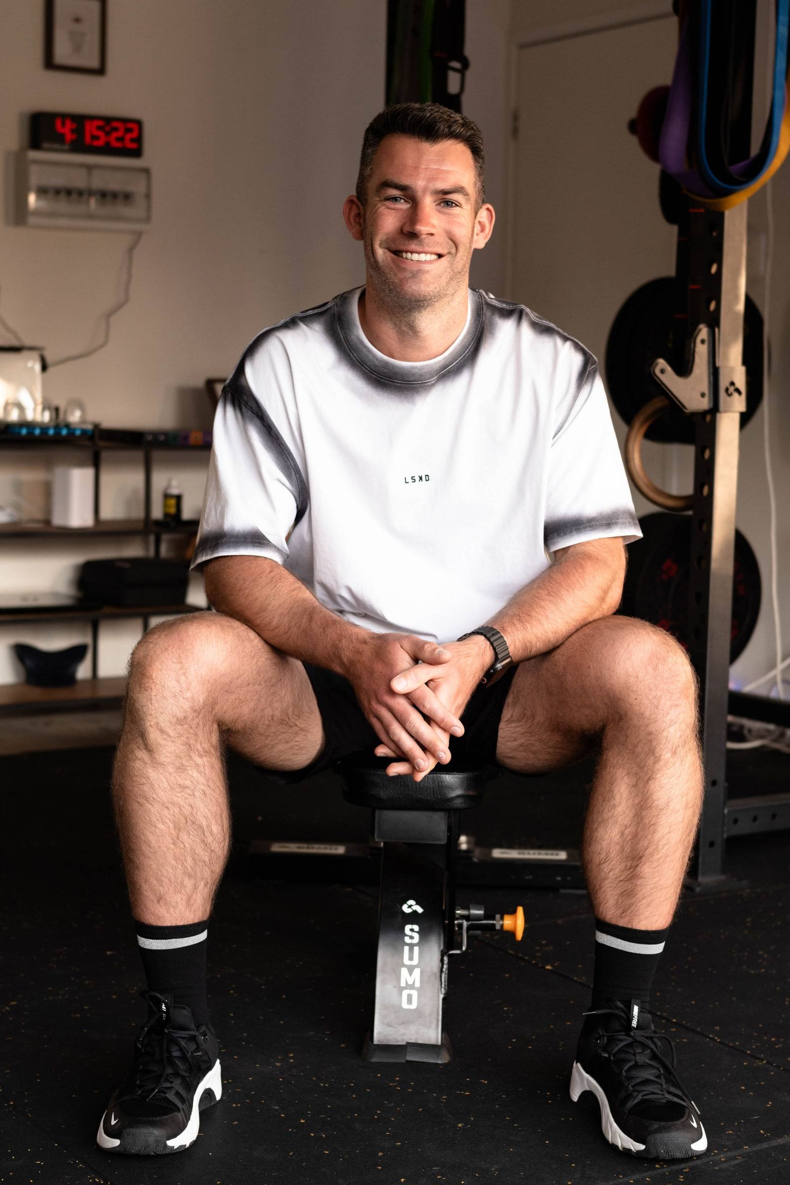 Richy sitting on a bench in the home gym, smiling